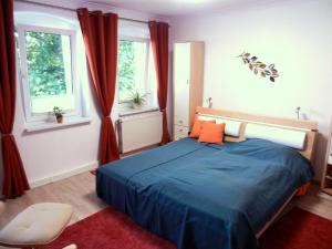 a bedroom with a blue bed and two windows at Ferienapartements Girrbach in Dresden