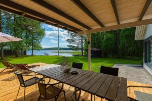 a patio with a wooden table and chairs on a deck at Villa Tuuliniemi in Muurame
