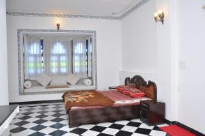 a bedroom with a bed and a window with a couch at Hotel Gangaur Palace in Udaipur