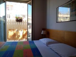 a bedroom with a rainbow bed and a large window at Ariston Petit Hotel in Palermo