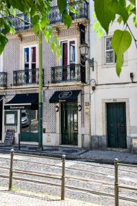 un bâtiment avec des portes vertes et une clôture devant lui dans l'établissement Santa Luzia B&B - HOrigem, à Lisbonne