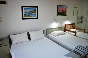 two beds in a room with white walls at Evaggelou Rooms in Potos