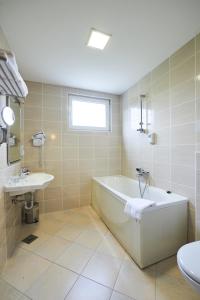 a bathroom with a tub and a sink at Hotel Korosica in Šentjanž pri Dravogradu