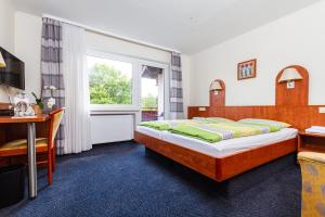 a bedroom with a bed and a desk and a window at Landhotel Georgshof in Hünfeld
