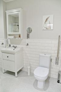 ein weißes Bad mit einem WC und einem Waschbecken in der Unterkunft Portofino Seaside Apartments in Misdroy