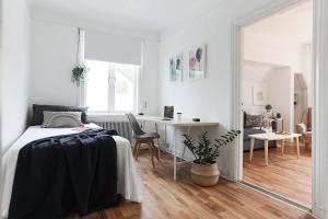 a white bedroom with a bed and a desk at Cozy Apartment in Uppsala