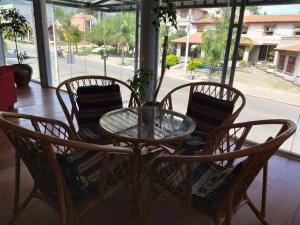 a glass table with four chairs and a table with a plant at Cana Blaya Apart Hotel in Merlo