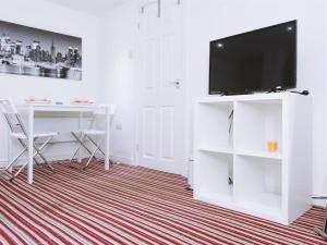 ein weißes Wohnzimmer mit einem TV und einem Schreibtisch in der Unterkunft Brownhill Studio in Leeds in Leeds