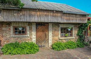 a stone house with a large wooden door and windows at Pie Pifa in Pāvilosta