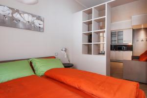 1 dormitorio con 1 cama de color naranja y cocina en UR-NEST Piazza Maggiore, en Bolonia