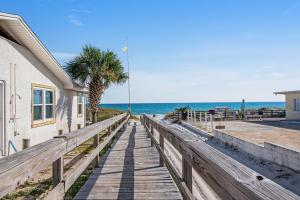 a wooden walkway to the beach with a palm tree at Tarpon 10 in Panama City Beach