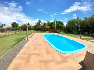 a swimming pool with a wooden floor and a blue pool at Recanto das Árvores Guriri in Guriri