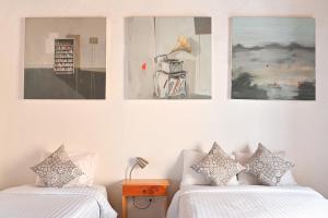 two beds in a room with pictures on the wall at Hotel Meson Cuevano in Guanajuato