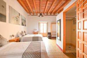 a bedroom with two beds and a hallway with a door at Hotel Meson Cuevano in Guanajuato