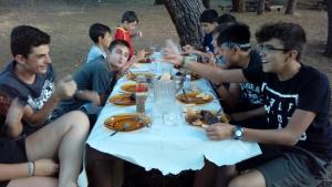 un grupo de hombres sentados alrededor de una mesa comiendo comida en Albergue Ciudad del Doncel, en Sigüenza