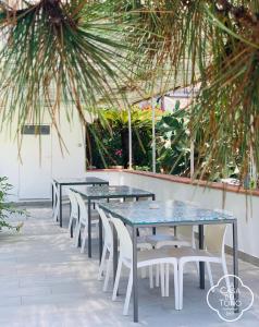 a row of tables and chairs with palm trees at La Casa Del Tono in Milazzo