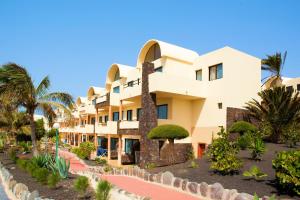 a building at the resort with palm trees at SBH Hotel Royal Mónica in Playa Blanca