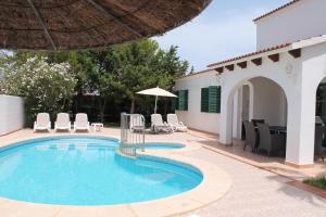una piscina con sedie e una casa di Villa RAQUEL a Cala'n Forcat