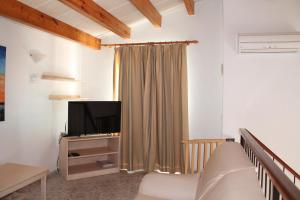 un soggiorno con un divano e una televisione di Villa RAQUEL a Cala'n Forcat