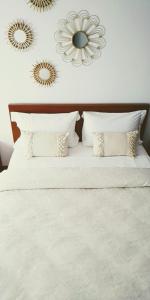 a white bed with pillows and mirrors on the wall at Mi Casa Su Casa in Montijo