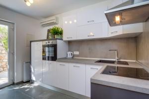 a kitchen with white cabinets and a sink at Leonida in Mali Lošinj