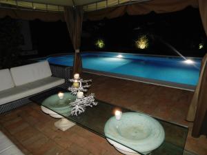 um pátio com uma mesa e uma piscina à noite em Appartamento con piscina immersa nel verde em Cascina