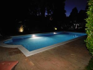 uma piscina à noite com luzes acesas em Appartamento con piscina immersa nel verde em Cascina
