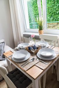 uma mesa de jantar com pratos brancos em Portofino Seaside Apartments em Międzyzdroje