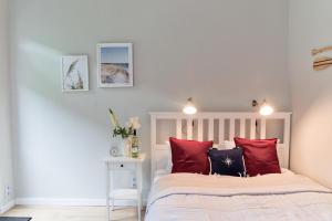 um quarto com uma cama branca e almofadas vermelhas em Portofino Seaside Apartments em Międzyzdroje