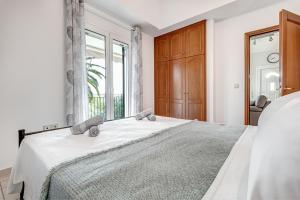 een witte slaapkamer met een groot bed en een raam bij Dream Garden Apartments Corfu in Kommeno