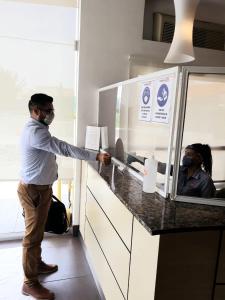 a man wearing a mask standing at a counter at Hotel Hi! Zapopan in Guadalajara