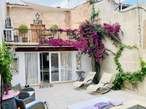 eine Terrasse mit Stühlen und lila Blumen auf einem Gebäude in der Unterkunft Can Raixa in Lloseta