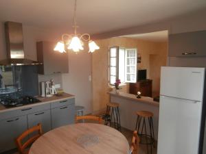 een keuken met een tafel en een witte koelkast bij La grange de Tombeloly in Clermont-de-Beauregard