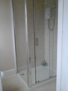 a shower with a glass door in a bathroom at Rob Roy Guest House in Folkestone