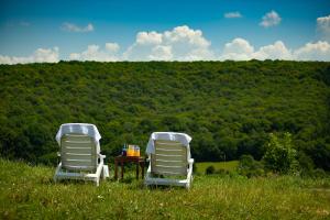 dos sillas blancas y una mesa en un campo en Saciova Hills, en Saciova