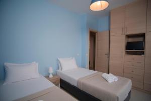 a bedroom with two beds and a cabinet with a tv at Elina's Maisonette in Episkopos