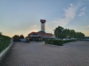 a parking lot with a control tower in the background at Hotel Motel 2 in Castel San Giovanni