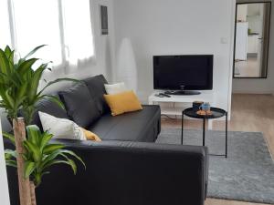 a black couch in a living room with a tv at RESIDENCE APPART CENTRE VILLE LORIENT Calme Garage in Lorient