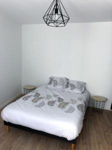 1 dormitorio con 1 cama blanca y 2 mesas en Appartement calme & lumineux proche centre, en Saumur