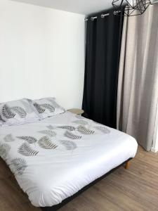 1 cama con sábanas blancas y cortina negra en Appartement calme & lumineux proche centre, en Saumur
