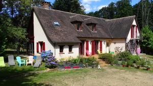 a white house with red doors and a yard with chairs and flowers at Chambres de Monthéard in La Bazoge