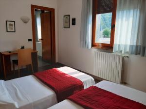 um quarto com duas camas e uma mesa e uma janela em La Ruota em Morbegno