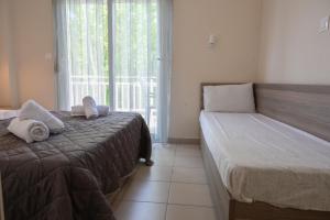a bedroom with a bed and a window with towels at Priona Rooms in Paralía Skotínis