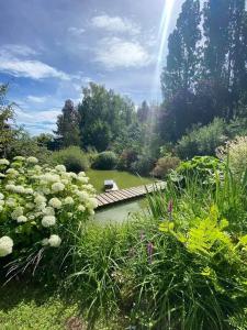 eine Brücke über einen Teich in einem Garten mit Blumen in der Unterkunft La Haie à Cerf in Watronville