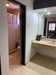 a bathroom with a sink and a toilet and a mirror at Hotel La Finca in Hermosillo