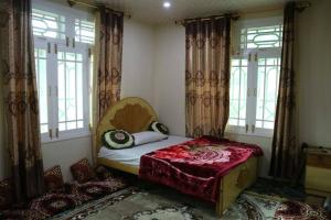 ein Schlafzimmer mit einem Bett in einem Zimmer mit Fenstern in der Unterkunft Hunza Heaven Guest House in Baltit