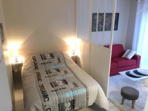a bedroom with a bed and a red couch at Charmant Studio 25 m2, 900m de la plage in Les Sables-d'Olonne