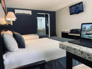 a hotel room with two beds and a laptop on a desk at Hotel La Finca in Hermosillo