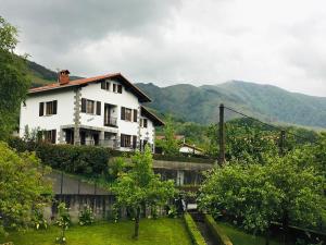 uma casa branca numa colina com montanhas ao fundo em EKIALDE rural em Arantza