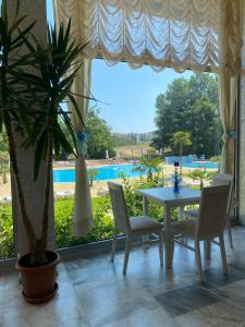 a dining room with a table and chairs and a pool at Kamenec Hotel in Nesebar